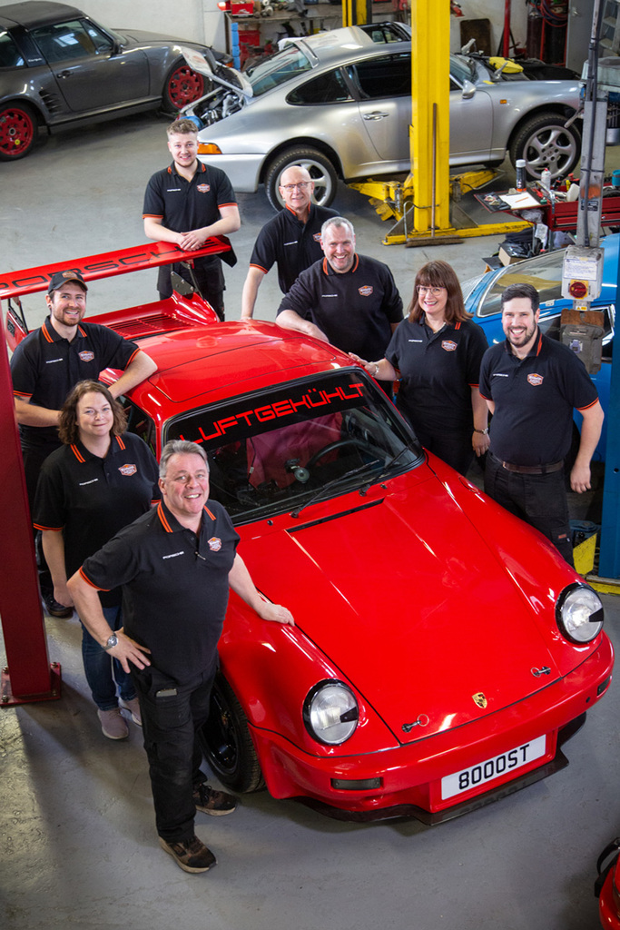 A Photo of the full team with a Red 911 Turbo